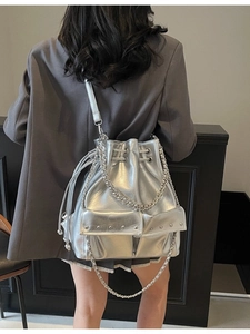 Metallic silver bucket bag with silver rivets and dual pockets for commuting style