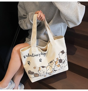 Detail of canvas tote bag with Valentine's Day cat print held on wooden stairs