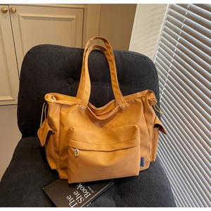 Detail of a ginger yellow canvas tote bag with side drawstring and front zipper pocket