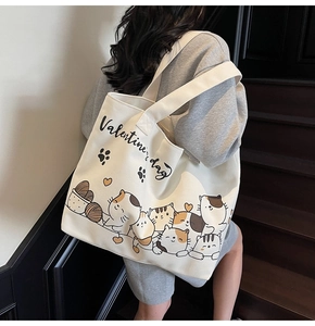 Detailed side view of off-white canvas tote bag with cartoon cat and heart prints