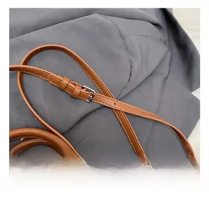 Detail of adjustable brown lychee-patterned leather strap with silver metal buckle