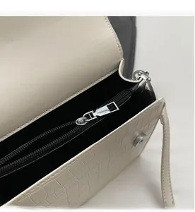 Close-up of smooth metal zipper and black lining inside the beige crocodile bag