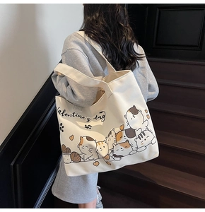 Detail of cartoon cat print on a cream canvas tote bag with wide shoulder strap