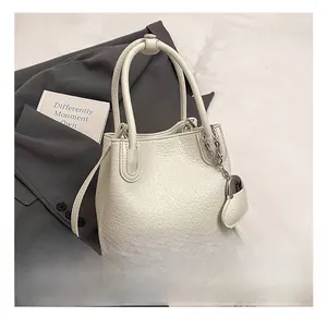Detail view of lychee pattern leather bucket bag with heart pendant on suit background