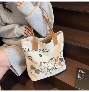 Detail of canvas tote bag with cartoon cat print and brown rope handles in lifestyle setting