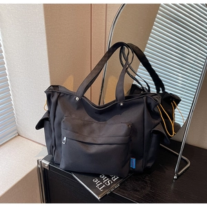 Detail of black canvas tote bag showing yellow drawstring pockets and metallic rivets