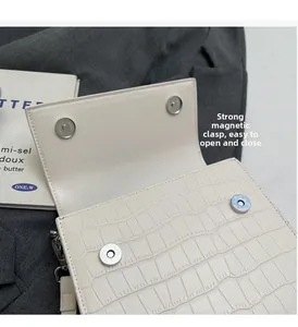 Detail of white crocodile texture handbag showing secure double magnetic snap closure