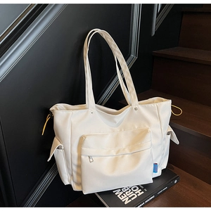 Detail showing the large front zipper pocket and yellow drawstring on a white canvas tote bag