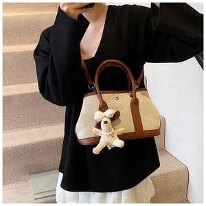 Detail of canvas bucket bag with brown leather trim and cute puppy plush charm accessory