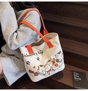 Detail of a large canvas tote bag with cat prints and orange straps on stairs