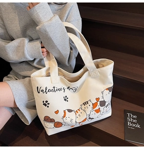 Detail of white canvas tote bag featuring cute cartoon cats and heart prints