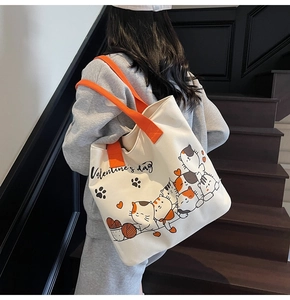 Detailed shot of a large canvas tote bag featuring cute cat prints and orange straps