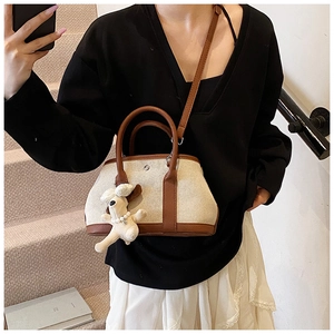 Detail of canvas mini tote bag with brown leather trim and cute puppy charm on handle