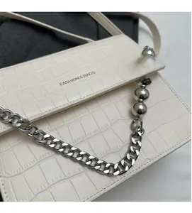 Detail of cream faux crocodile leather bag with chunky silver chain and pearl accents
