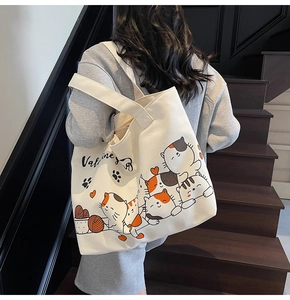 Detail of a large white canvas tote bag with colorful cartoon cat prints and black text