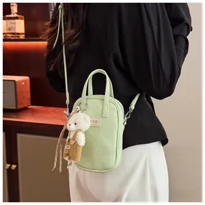 Detail of mint green lychee leather mini crossbody bag with cute white bear charm