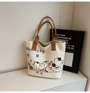 Detail of canvas tote bag with cartoon cat prints and brown woven handles