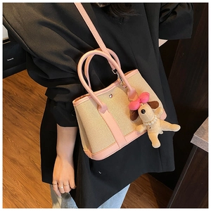 Detail of canvas tote bag with pink leather trim and cute plush puppy charm accessory