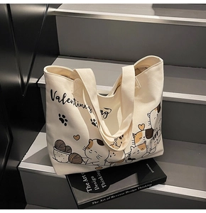 Detailed macro view of cream canvas tote bag with cute cartoon cats and script text