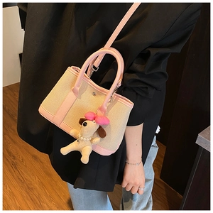 Detail of a chic contrast canvas bucket bag with pink leather trim and a cute puppy charm