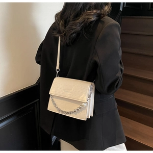 Detail view of cream crocodile textured crossbody bag with silver chain and pearl decor