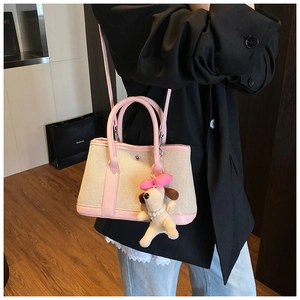 Detail of canvas tote bag with pink leather trim and cute puppy charm on mannequin