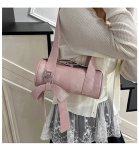 Détail du sac cylindrique rose avec nœud surdimensionné et anneau métallique argenté