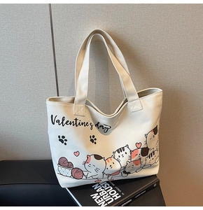Close-up of Valentine's Day cartoon cat prints on a beige canvas tote bag surface