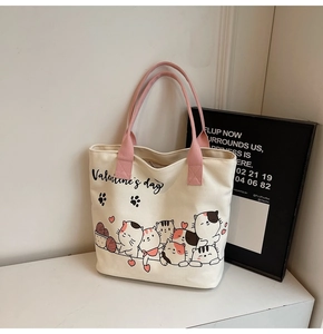 Detail of canvas tote bag featuring Valentine's Day cat print and pink woven handles