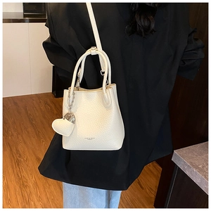Detail of off-white lychee grain bucket bag with heart charm and brand logo lettering