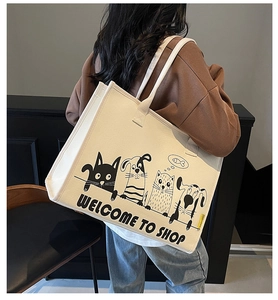 Große cremefarbene Canvas-Einkaufstasche mit niedlichen Comic-Tiermotiven am Model