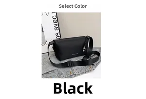 Détail d'un sac bandoulière noir mat avec sangle nylon et breloque en métal sur denim