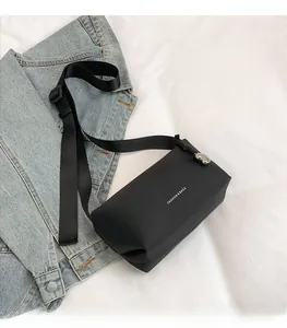 Détail d'un sac bandoulière en nylon noir avec texte mode et breloque coeur argentée