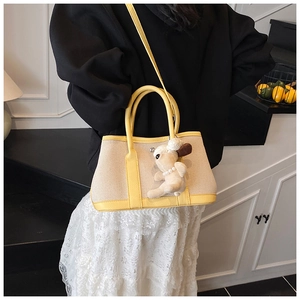 Detail of color-block canvas tote bag with yellow leather trim and cute lamb pendant charm