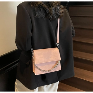Pink croc-embossed crossbody bag featuring silver chain strap with pearl charms detail