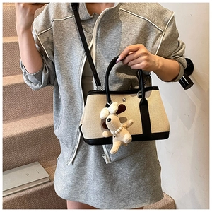 Detail of canvas bucket bag with black leather trim and cute puppy charm for women