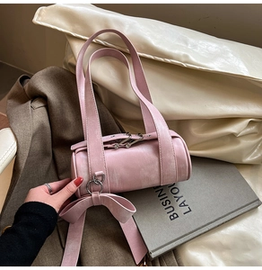 Sac Boston rose en cuir avec grand nœud et anneaux argentés dans un cadre lifestyle