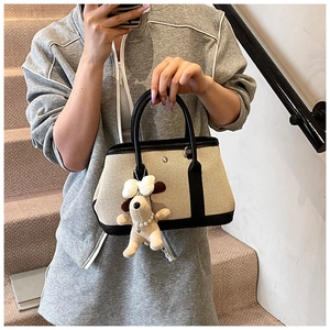 Detail of canvas tote bag with contrast leather trim and plush snoopy charm