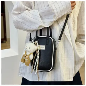 Mini black leather crossbody bag with white piping and cute teddy bear pendant charm