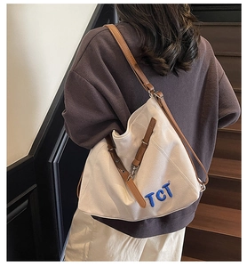 Detailed back view of a canvas tote bag with brown leather straps on a model
