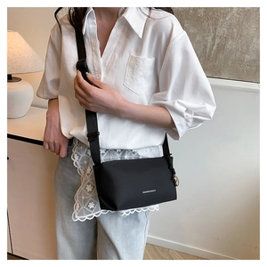 Détail du sac bandoulière noir en nylon avec sangle réglable et texte décoratif