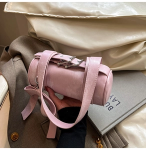 Détail du sac polochon rose montrant la texture cuir et le nœud décoratif élégant