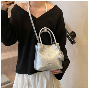 Silver bucket bag with litchi texture and heart charm shown in a model lifestyle shot