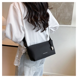 Vue latérale d'un sac bandoulière noir avec texte blanc et pendentif en argent