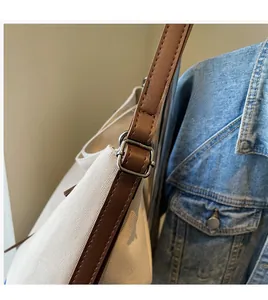 Detail of adjustable brown leather strap and metal buckle on canvas tote bag