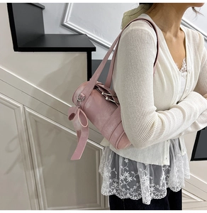 Gros plan du sac Boston rose cylindrique avec un grand nœud décoratif et anneaux argentés