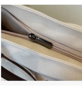 Macro shot of the smooth gunmetal zipper and dark brown strap on a canvas tote bag