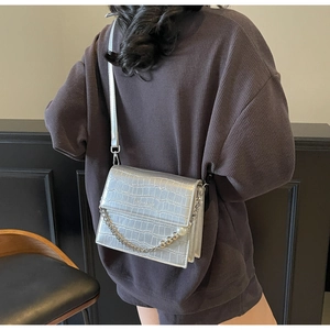 Close-up of silver crocodile embossed faux leather crossbody bag with pearl chain detail