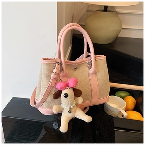 Detail of pink and beige canvas bucket bag with cute plush dog pendant on wooden table
