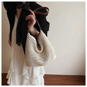 Detail of cream woven tote bag featuring brown leather handles and intricate crochet texture